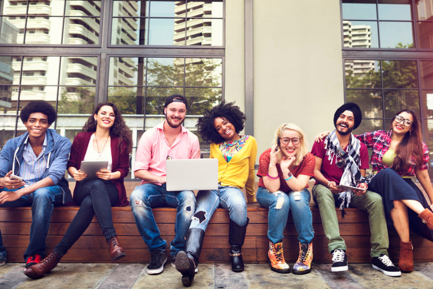 group of diverse young adults sitting together outside