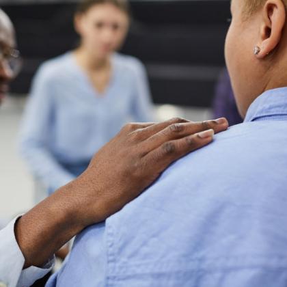 Image of man comforting someone in a group support or therapy session