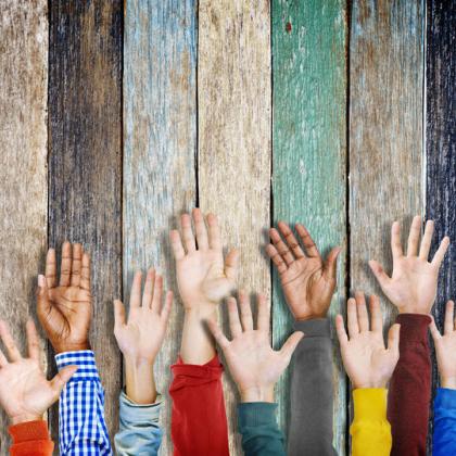 Diverse hands raised in front of colored wooden fence background